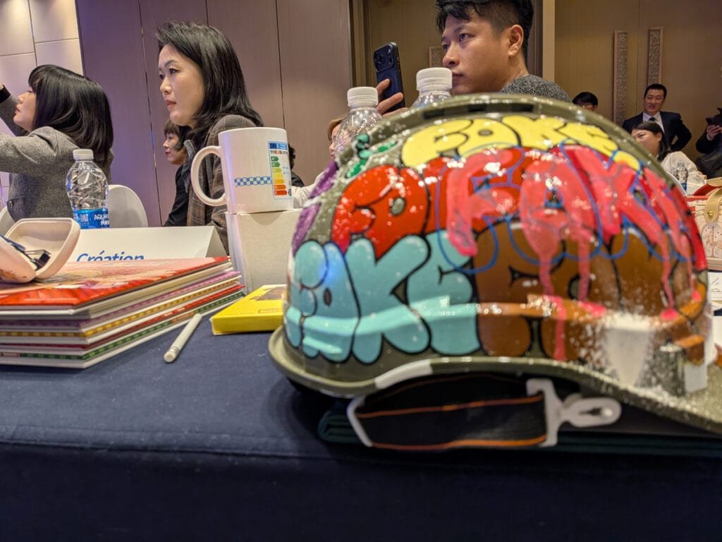 Photo du stand B2B des canards Volants en Chine. On y voit des BDs et des produits dérivés de Thérébentine. Au premier plan on voit un casque graffé par Marcel Champion.